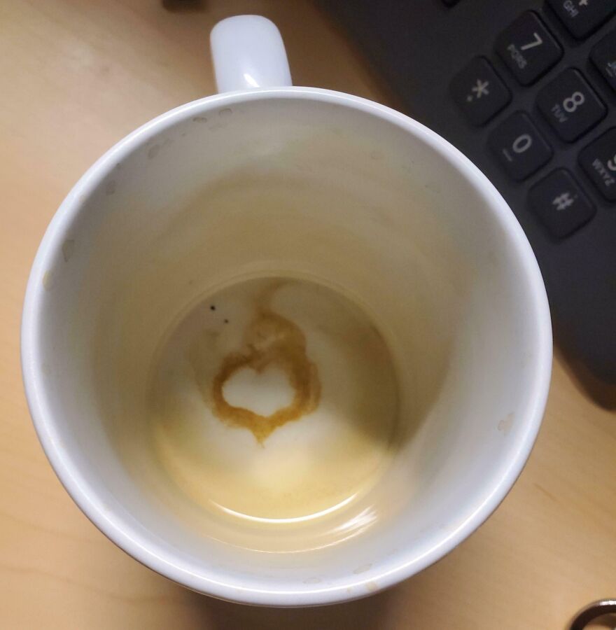 Coffee stain at the bottom of a mug shaped like a heart, resembling other objects on a desk setting.