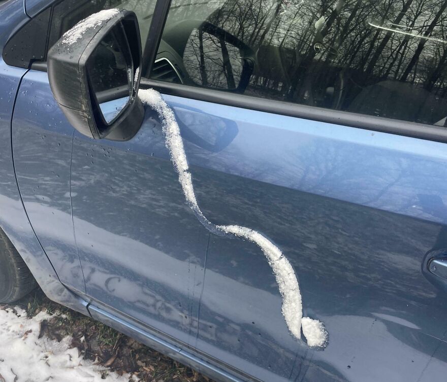 Snow on a car door resembles a musical note on a blue vehicle.