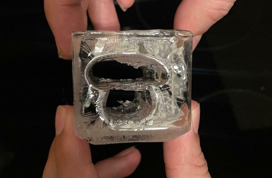 Ice cube shaped like a bottle opener held between fingers.