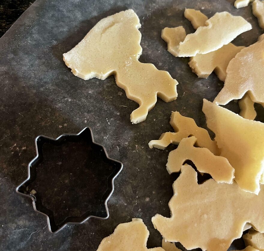 Cookie dough pieces cut into unusual shapes on a baking sheet, resembling other objects or maps.