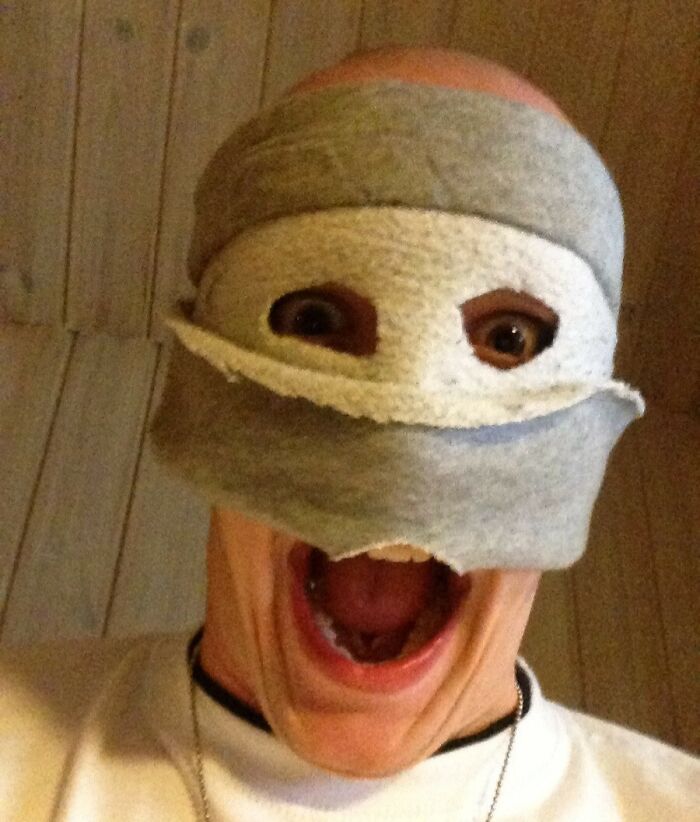 Person with a surprised expression, face wrapped in gray fabric, capturing a humorous moment for funny camera roll finds.