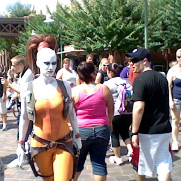 Cosplayer in orange costume with white face paint amusing a crowd, illustrating funny camera roll finds.