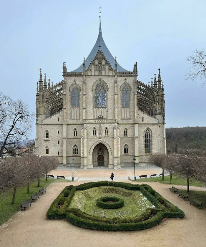 Gothic church with intricate architecture and a manicured garden in front, showcasing fascinating church design.