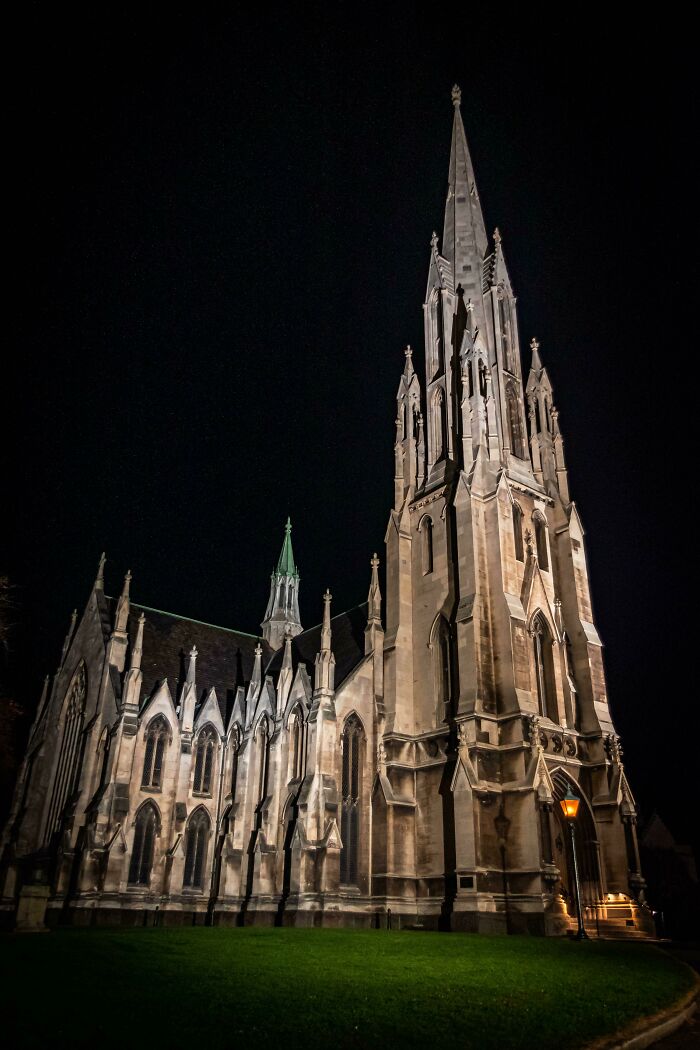 Gothic-style church at night, illuminated against the dark sky, showcasing intricate architecture.