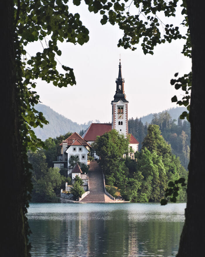 Stunning church nestled on an island surrounded by tranquil lake waters and lush greenery.