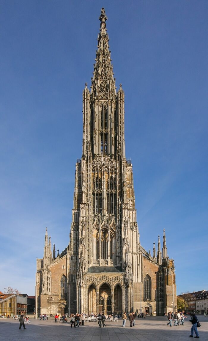 Gothic architecture of a cathedral with a tall spire under a clear blue sky, highlighting fascinating church details.