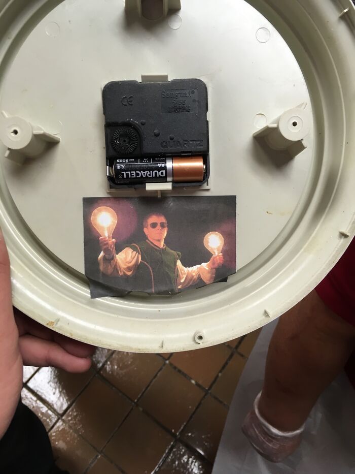 Clock interior with battery, featuring a photo of a person holding two glowing bulbs, related to people quitting jobs.