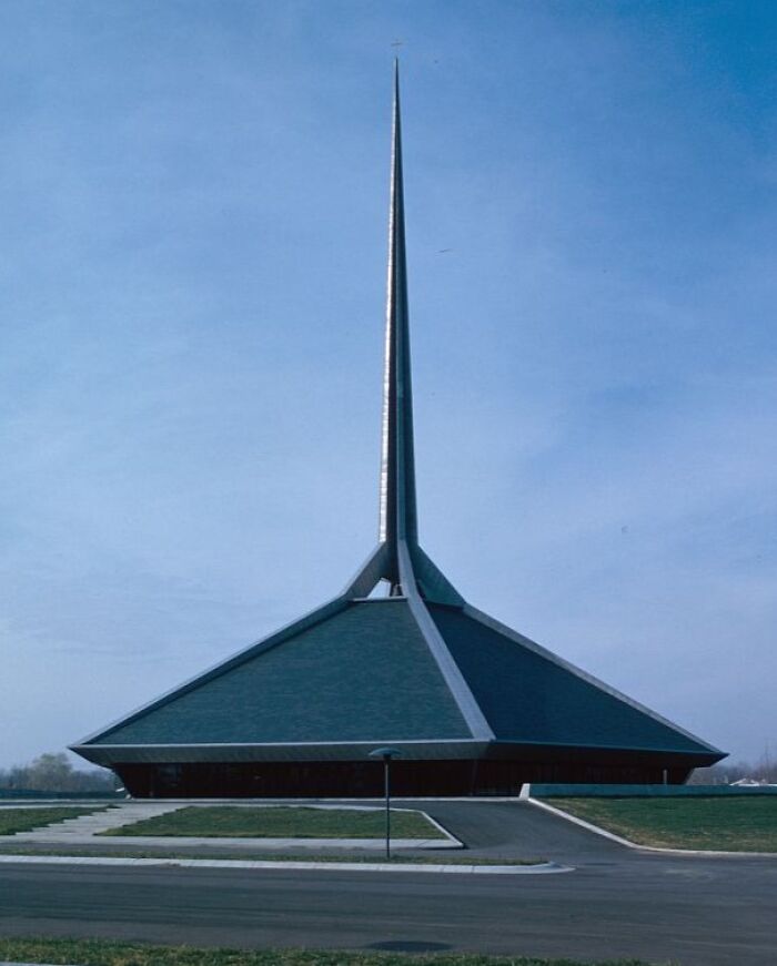 Unique modern church with a tall spire reaching into the clear blue sky, exemplifying fascinating architecture.