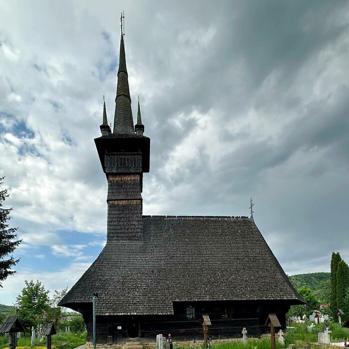 Wooden church with a tall spire against a cloudy sky, capturing fascinating church architecture.