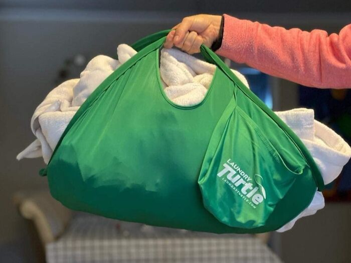 A green laundry bag labeled "Laundry Turtle" holding towels, demonstrating a less-mess solution.