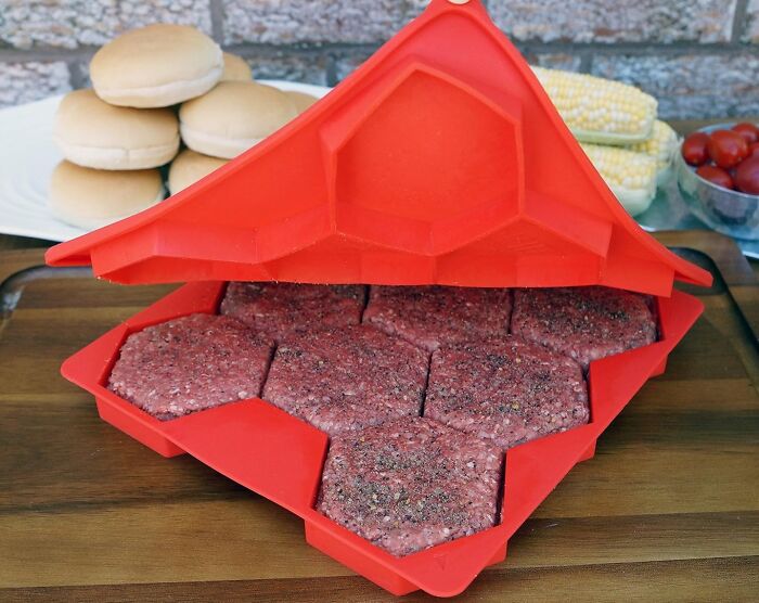 Red burger press with raw patties on a table, offering a Less-Mess solution for making even burger portions.