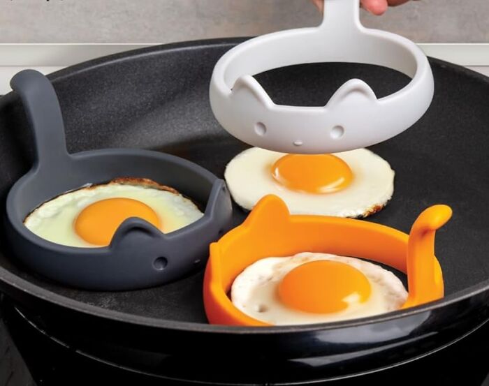 Eggs frying in quirky cat-shaped molds, adding fun and functionality to cooking.