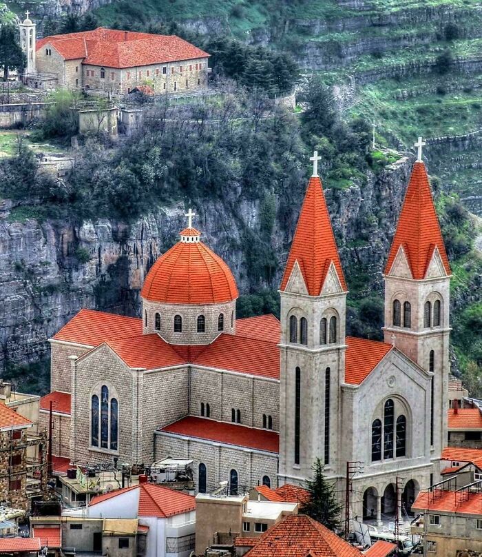 Stunning red-roofed church nestled in lush green mountains, showcasing captivating architecture.