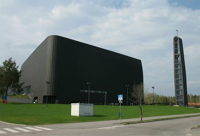 Modern black church building with a tall bell tower on a bright day.