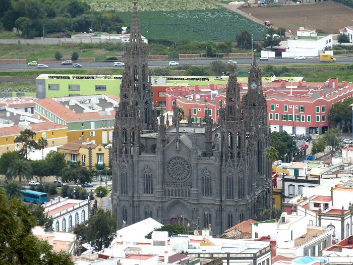 Gothic-style church amidst colorful town buildings with surrounding greenery.