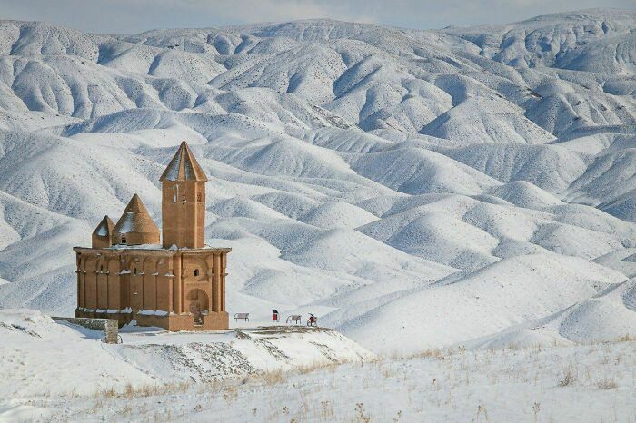 Snow-covered church surrounded by vast, snow-laden hills, capturing the essence of fascinating church scenery.