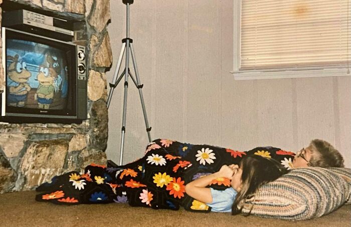 Children watching cartoons on a 1980s TV, covered with a floral blanket, evoking 80s nostalgia.