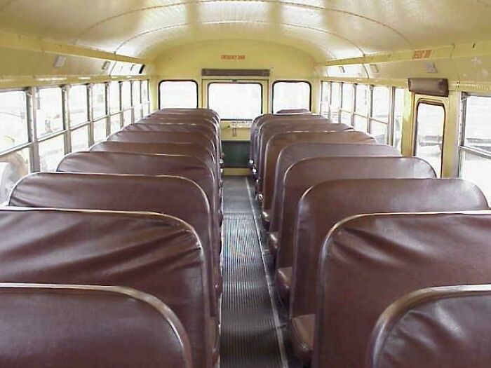 Interior of a vintage 80s school bus with brown seats and yellow walls, evoking nostalgic memories.