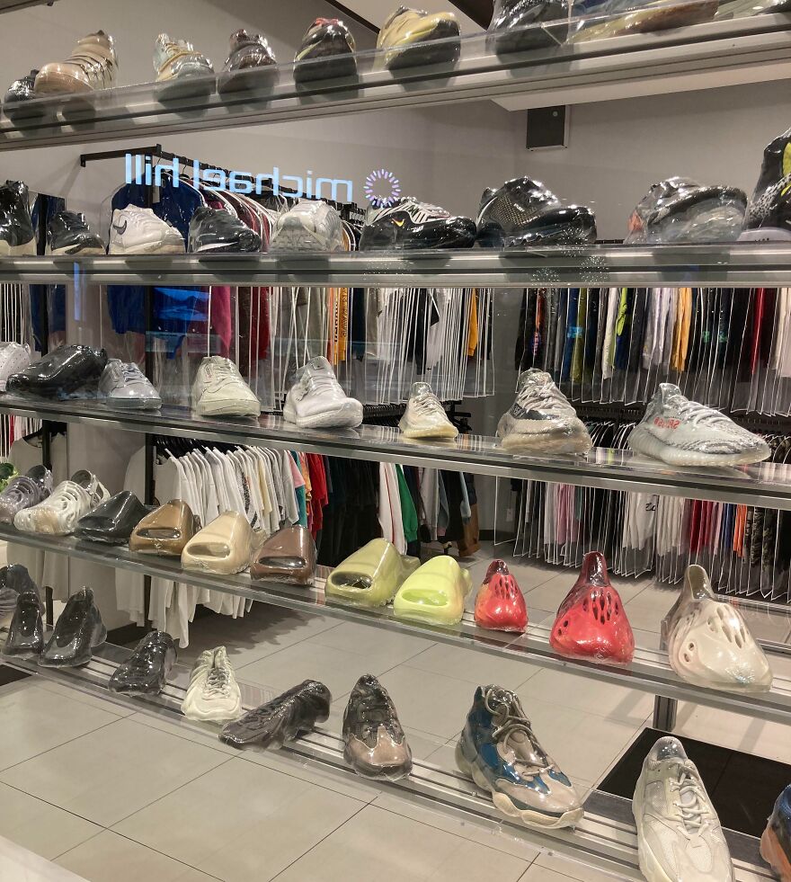 Sneakers wrapped in plastic, highlighting wasteful unnecessary packaging, displayed on shelves in a clothing store.