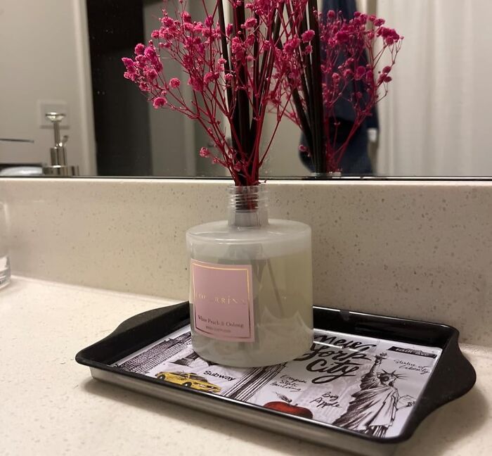 Cozy product: scented diffuser with pink dried flowers on a bathroom counter.