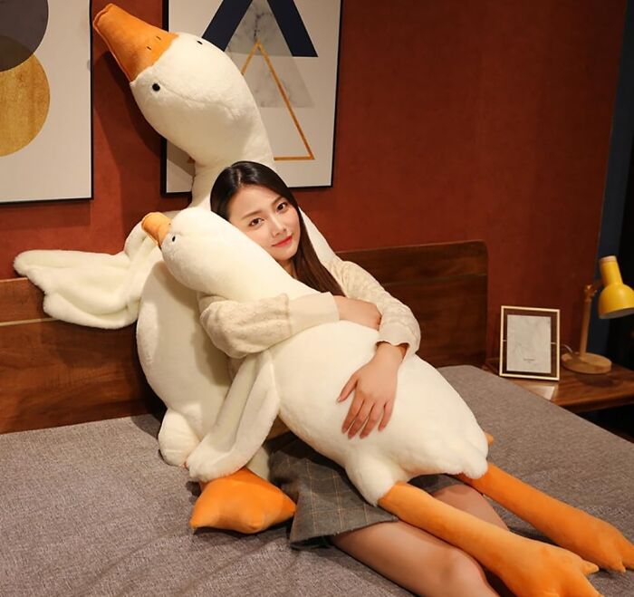 Woman relaxing with cozy plush ducks on a bed indoors.