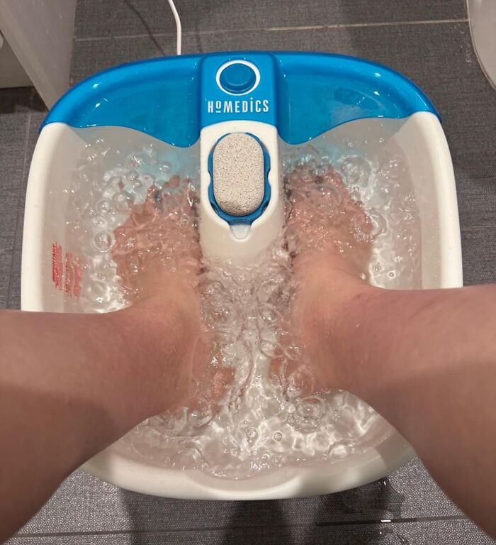 Feet soaking in a blue and white foot spa, ideal cozy product for relaxing indoors.