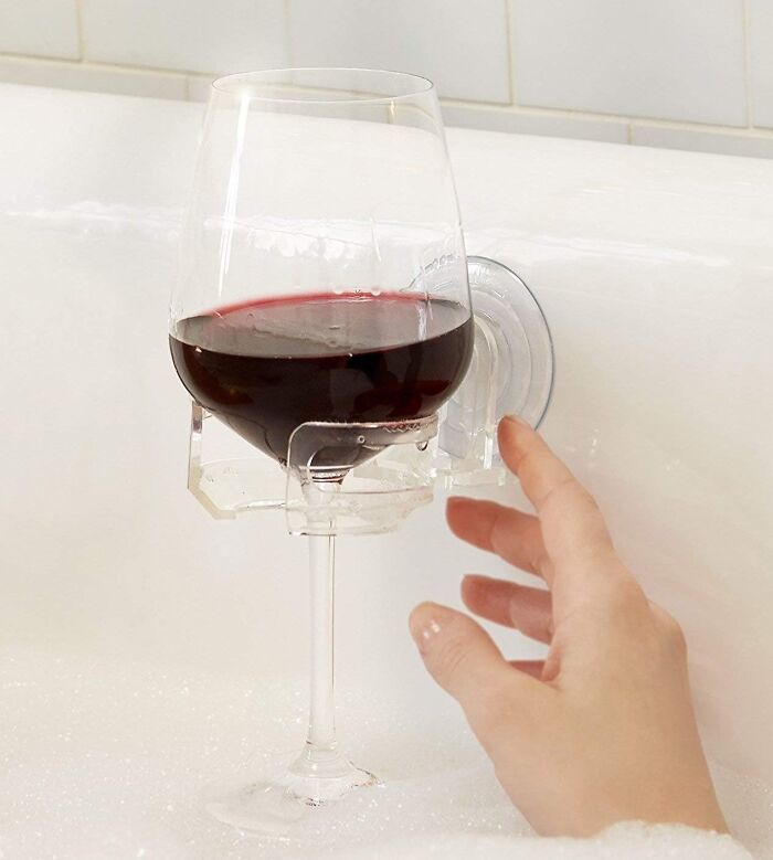 A glass of wine in a bath cup holder, ideal for cozy relaxation indoors.