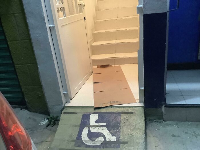 Entrance to a local pharmacy with a wheelchair ramp leading to stairs, highlighting accessibility issues.