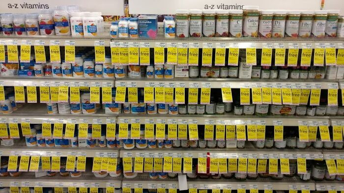 Shelves in local pharmacies displaying various vitamins, with numerous yellow sale tags.