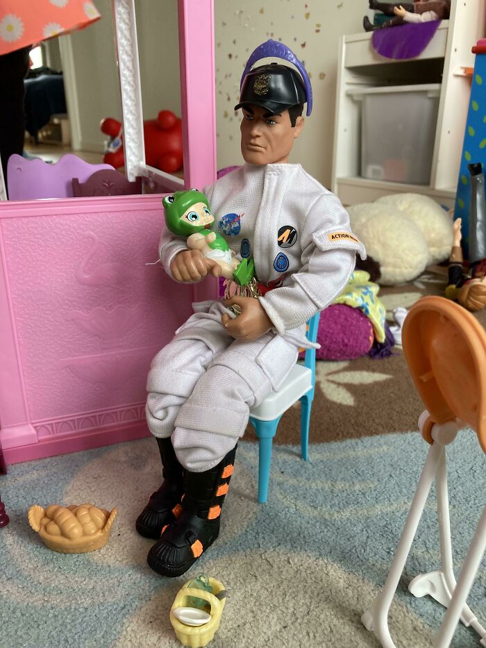 Toy astronaut holding a green plush frog in a colorful playroom. Hilarious-Kids themed play setup.