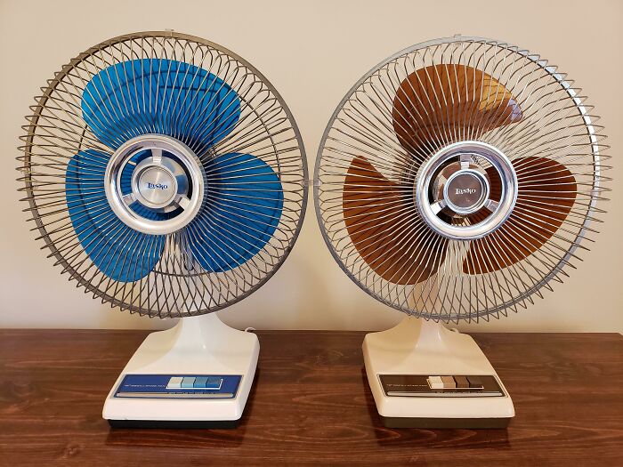 Retro 80s fans with blue and brown blades on a wooden table.