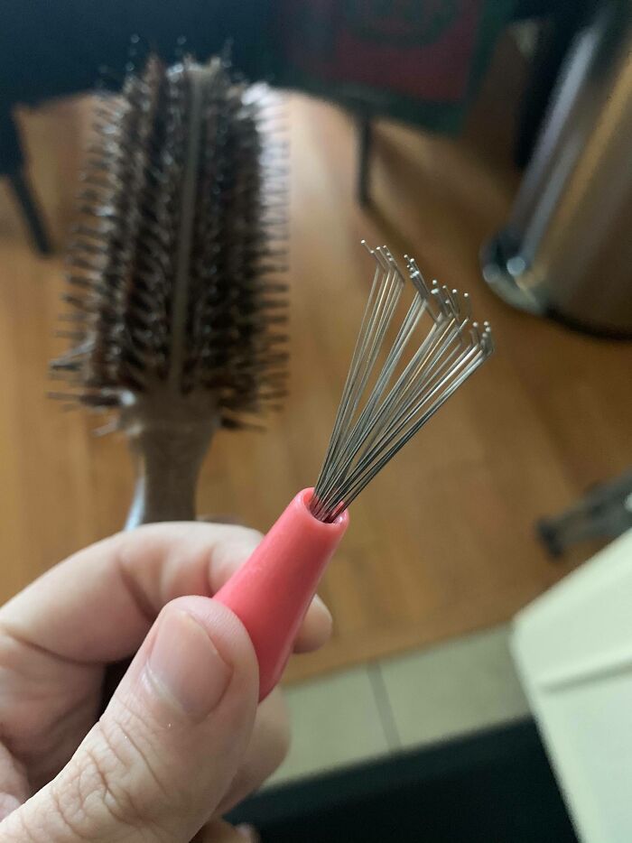 A hidden brush cleaner is revealed from a round hairbrush, showcasing cool products with surprises for easy maintenance.