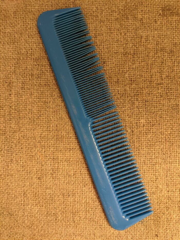 Blue plastic comb on a burlap background, evoking 80s nostalgia.