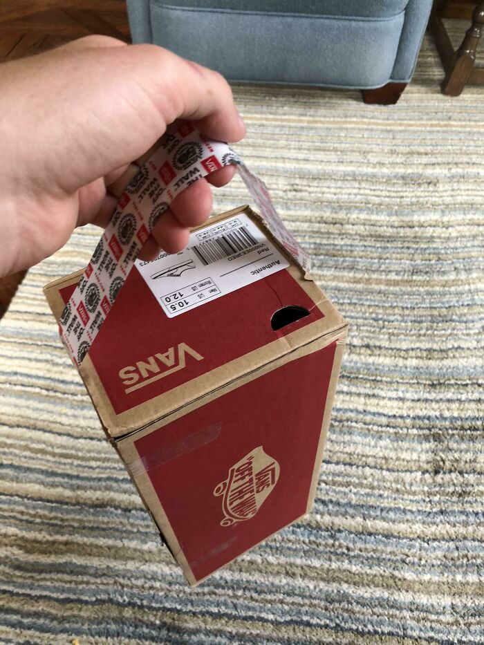 A hand holding a Vans shoe box with a surprise hidden storage feature.