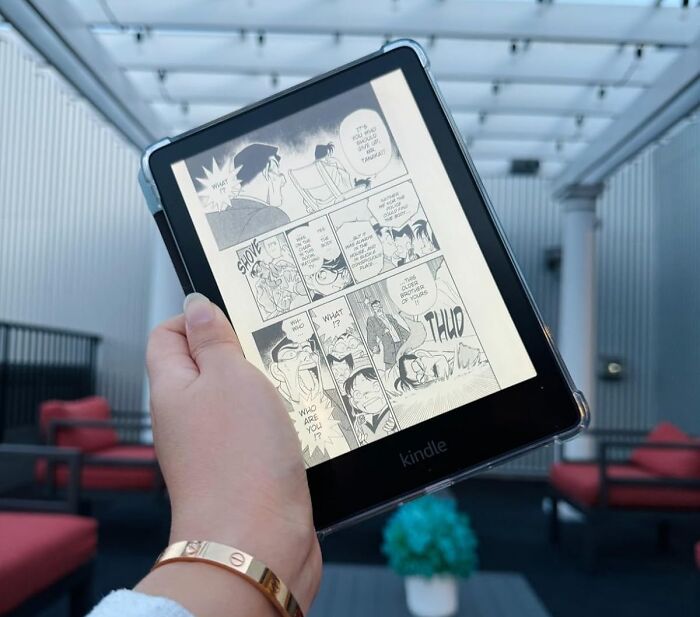 Hand holding a Kindle displaying a manga page, perfect for unwinding with irresistible treasures after a busy day.