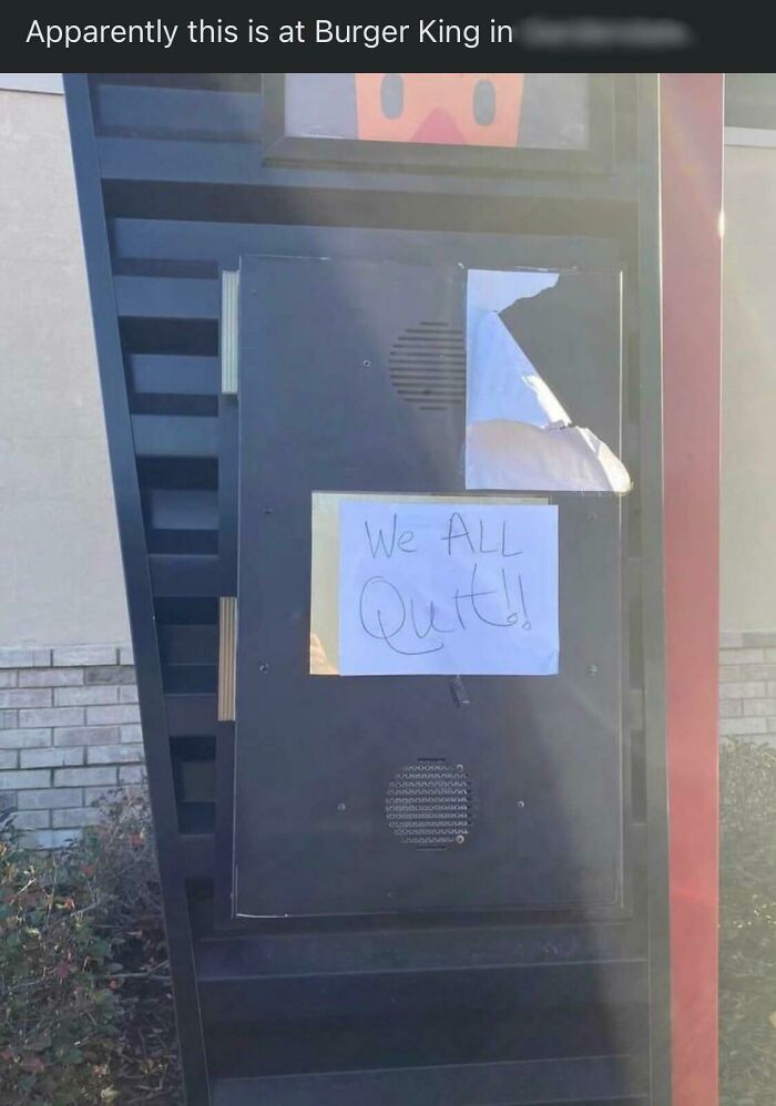 Burger King drive-thru sign with handwritten note saying "We ALL Quit!", highlighting people quitting jobs.