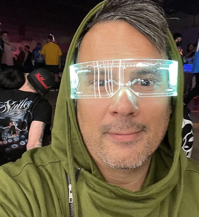 Man wearing futuristic glowing glasses, showcasing one of the best gadgets for 2025, dressed in a green hoodie.