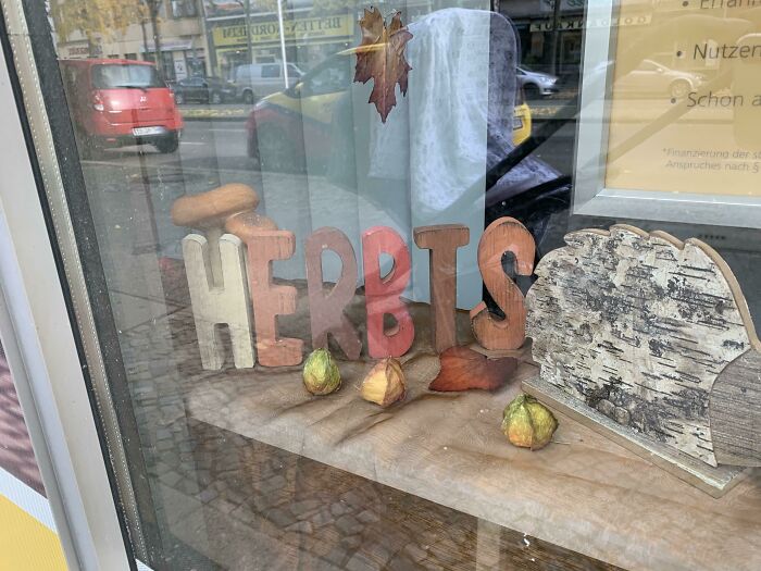 Autumn-themed pharmacy window display with seasonal decorations and the word "HERBST."