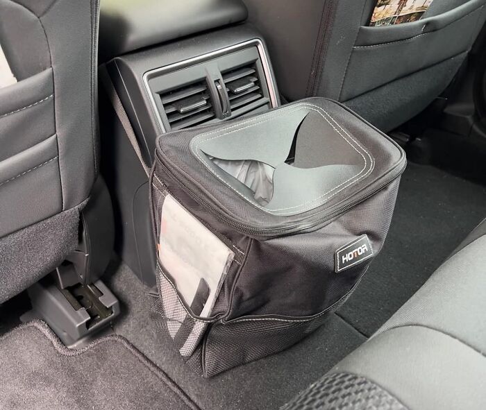 Car interior with a black trash bin placed on the floor, symbolizing responsibility and cleanliness for the new year.