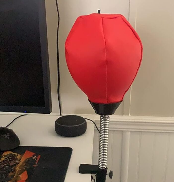 Red desktop punching bag next to a computer monitor, showcasing a fun office supply.