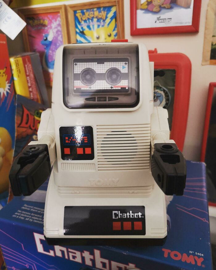 80s nostalgia picture featuring a vintage robot toy with cassette tape face, surrounded by retro game posters.