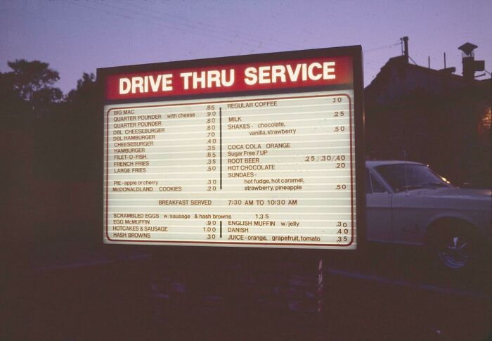 80s nostalgia picture of a vintage drive-thru menu board at dusk, featuring classic fast-food items and prices.