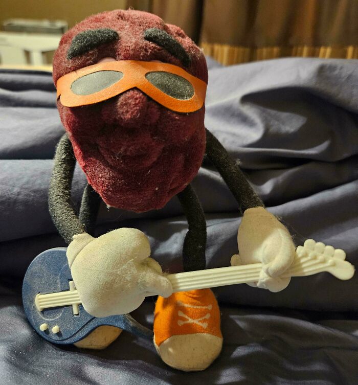 Plush toy with sunglasses and guitar, embodying 80s nostalgia.