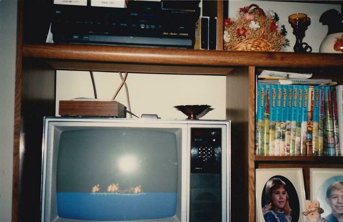 80s nostalgia picture with a vintage television, retro gaming console, and old books on a wooden shelf.