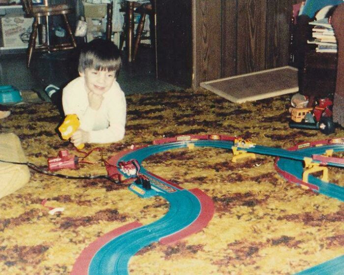 Child playing with a vintage slot car track on retro carpet, capturing 80s nostalgia.