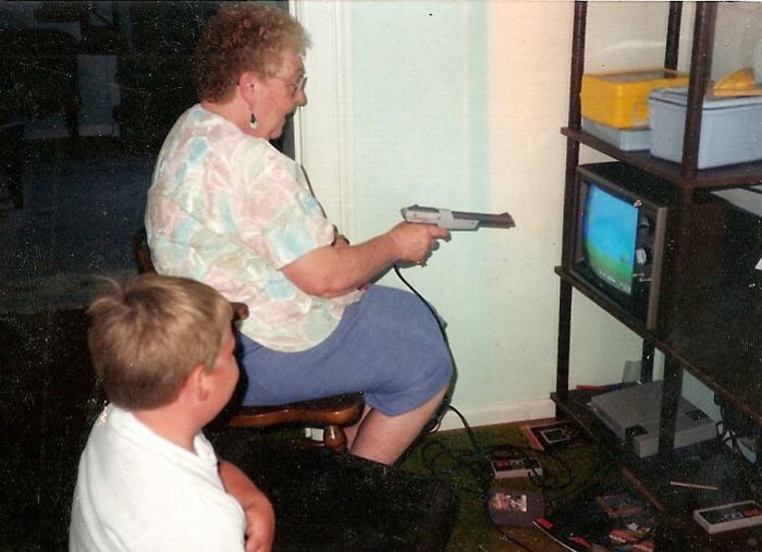 Grandmother playing video games on a vintage TV setup, capturing 80s nostalgia.