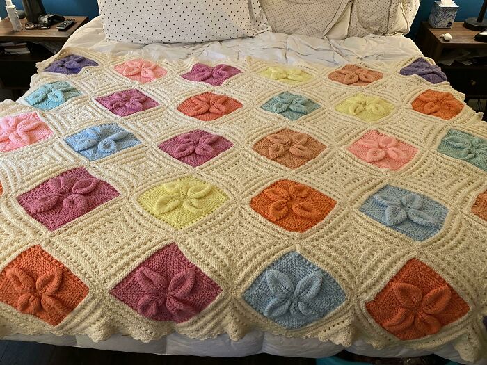 Crocheted blanket with colorful 80s nostalgia patterns on a bed.