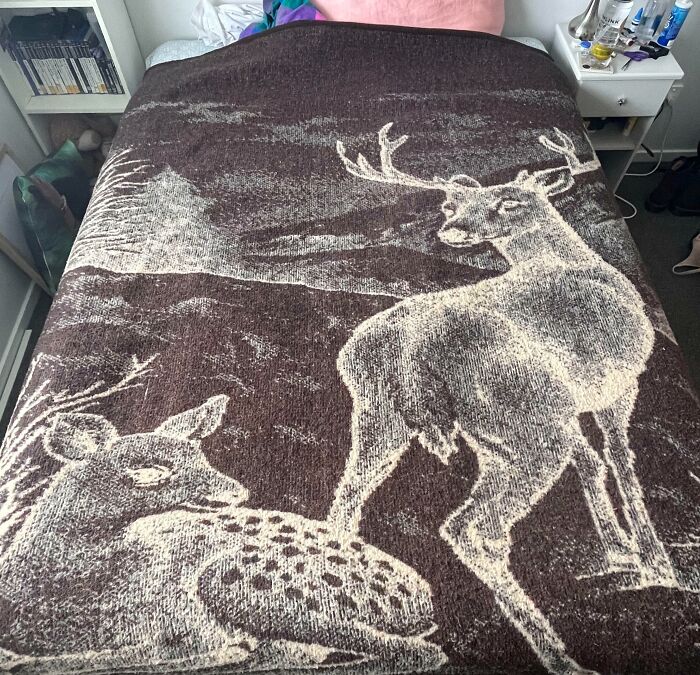 80s nostalgia deer blanket with a doe and stag design on a bed.