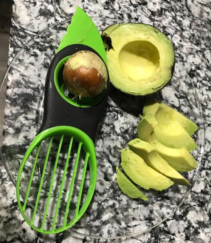 Avocado sliced with a green tool on a countertop, enhancing cooking skills.