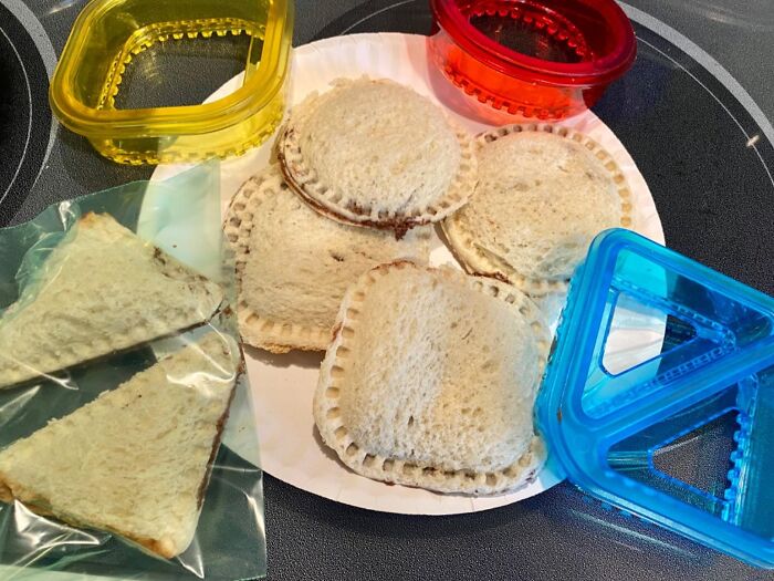 Uncrustable sandwiches on a plate with colorful cutting tools for cooking practice.